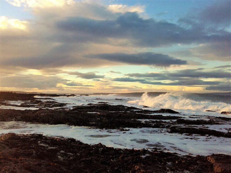 Waves breaking over seaweed at sunset in Caithness